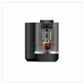 A modern  automatic coffee machine in dark gray and black, shown with a glass of iced coffee on its drip tray against a white background.